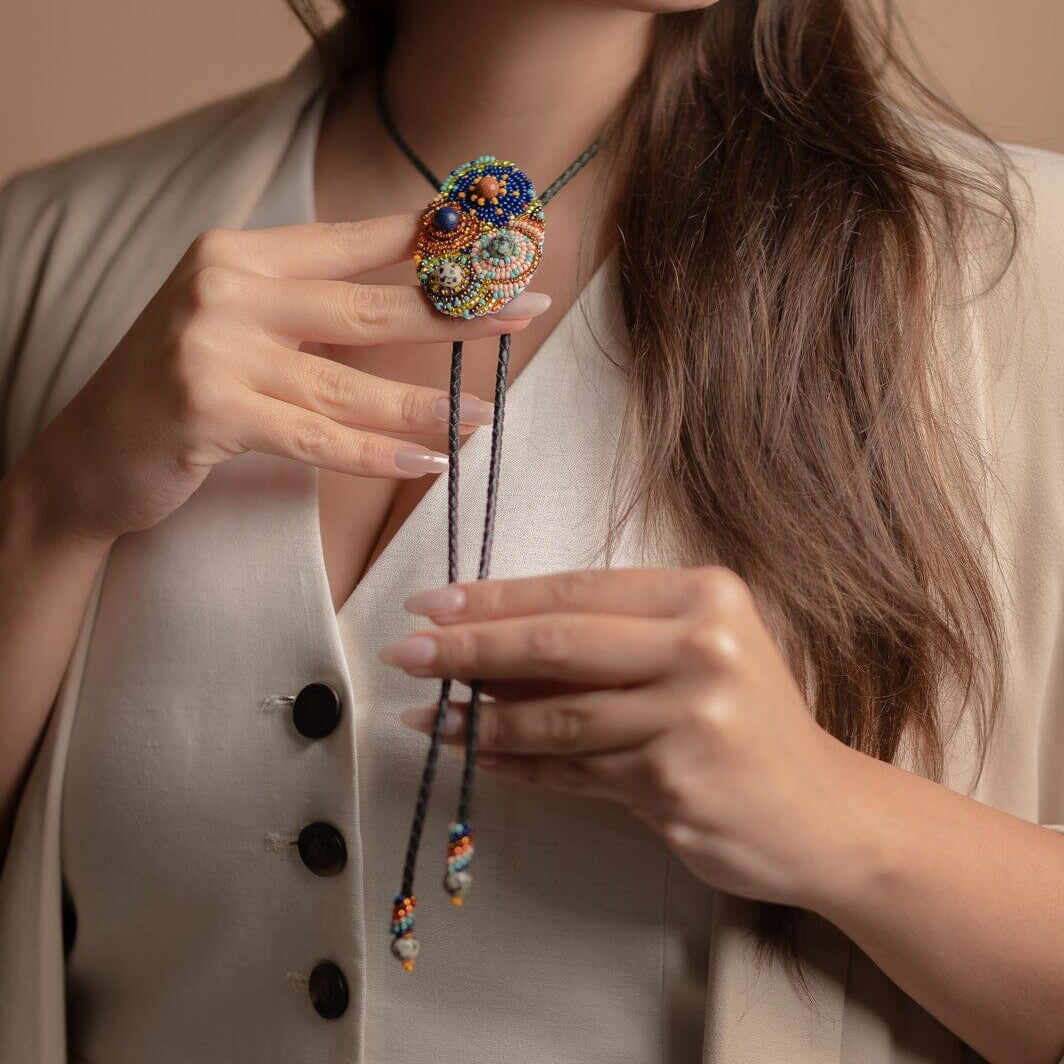 woman wearing bourbon cowgirl Bolo Tie blue red gold pink textured beaded necklace beaded native american jewelry mexico guatemala handmade accessory aglets slide clasp