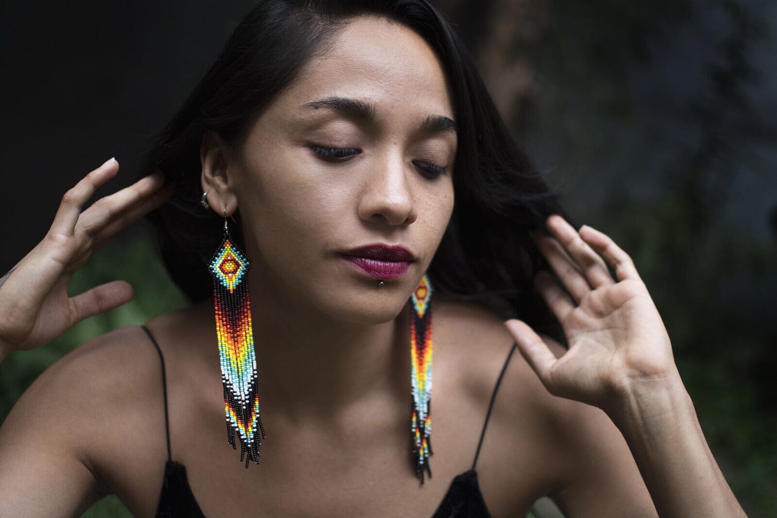 woman wearing black fire teal white red fringe beaded earrings