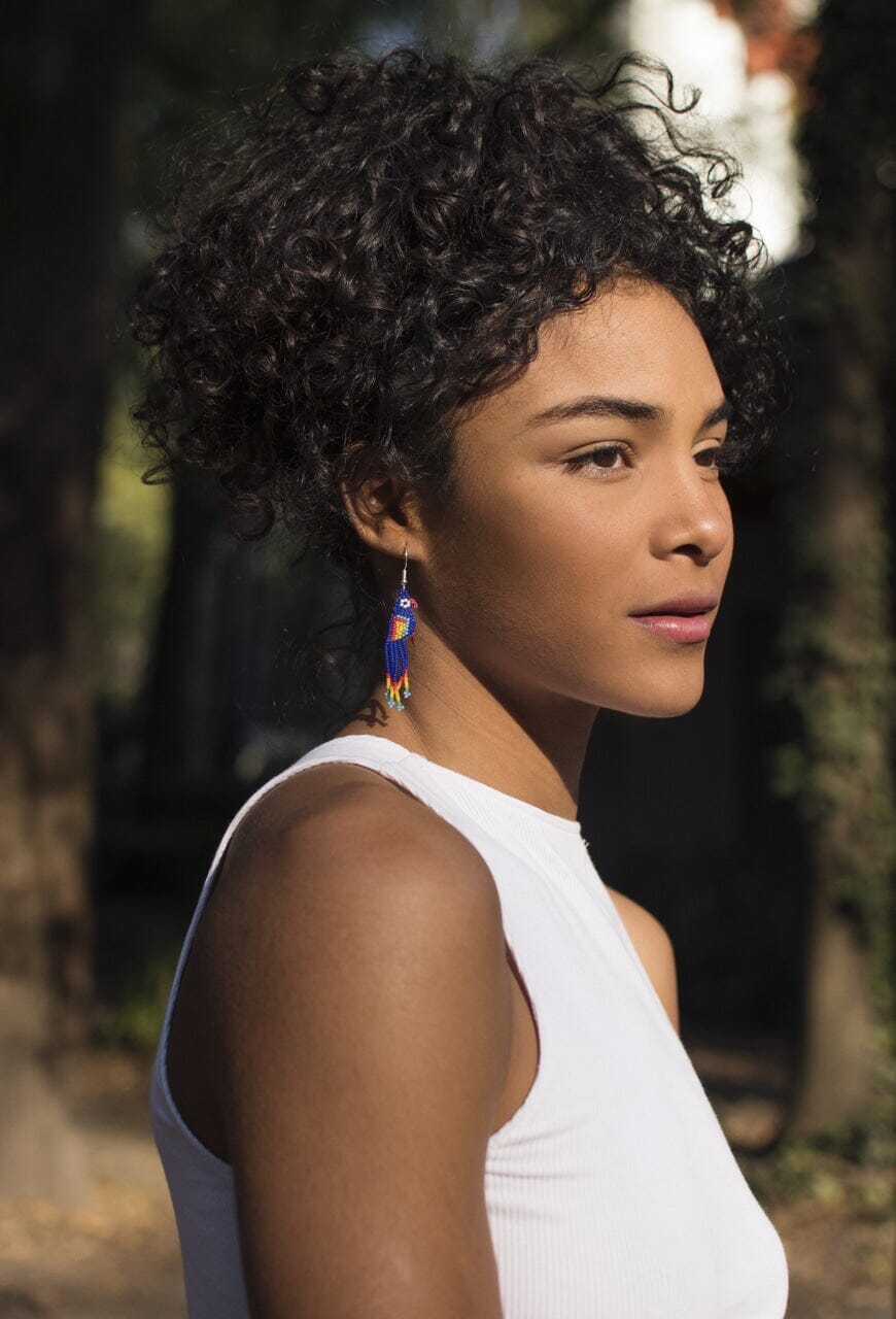 woman wearing bright blue bird beaded earrings