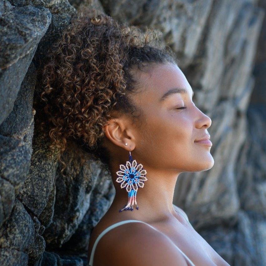 woman wearing Guanábana light blue eggshell white beaded earrings against rock wall