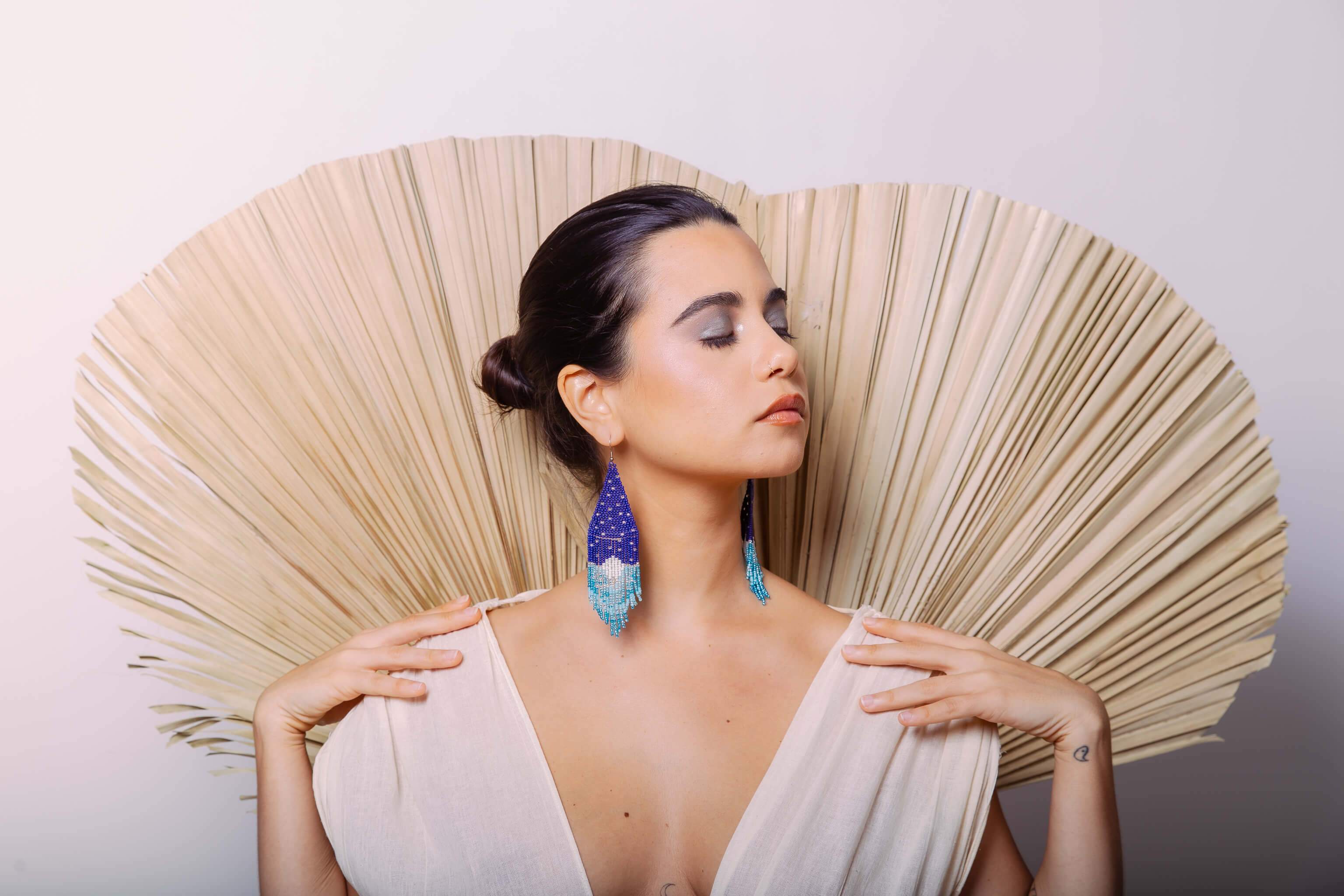 woman wearing blue white stars and moon night sky interstellar fringe beaded earrings