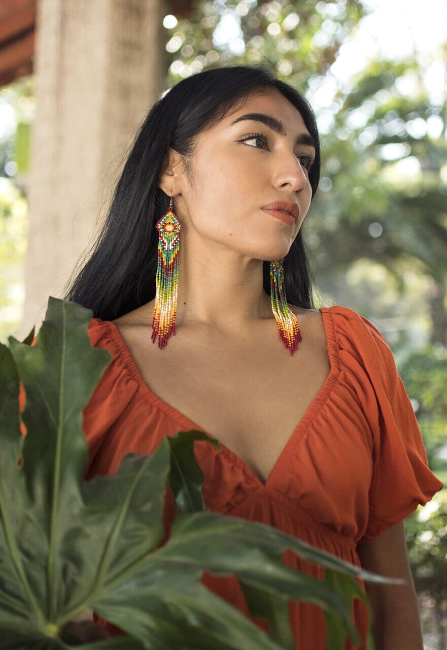 woman wearing brown green yellow white fringe beaded earrings