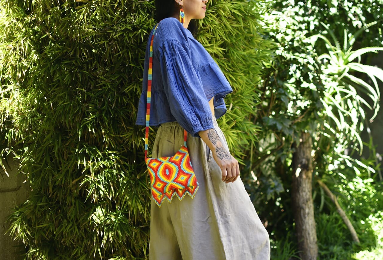 woman wearing yellow orange red teal mania beaded purse bag fringe