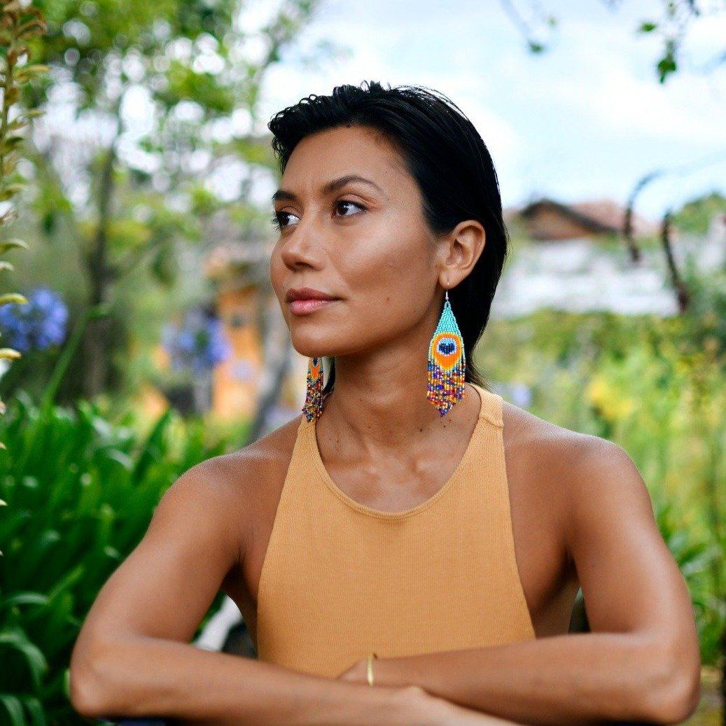 woman wearing blue orange peacock feather fringe beaded earrings