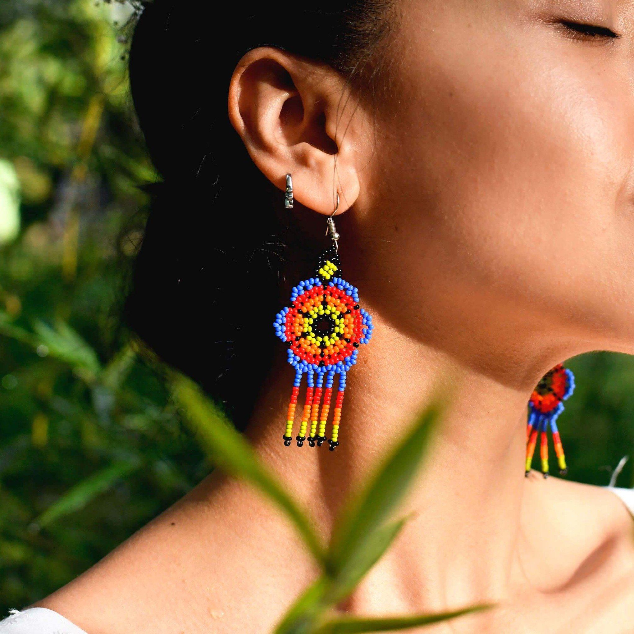 woman wearing psychedelic blossom blue green red beaded earrings in sunlight