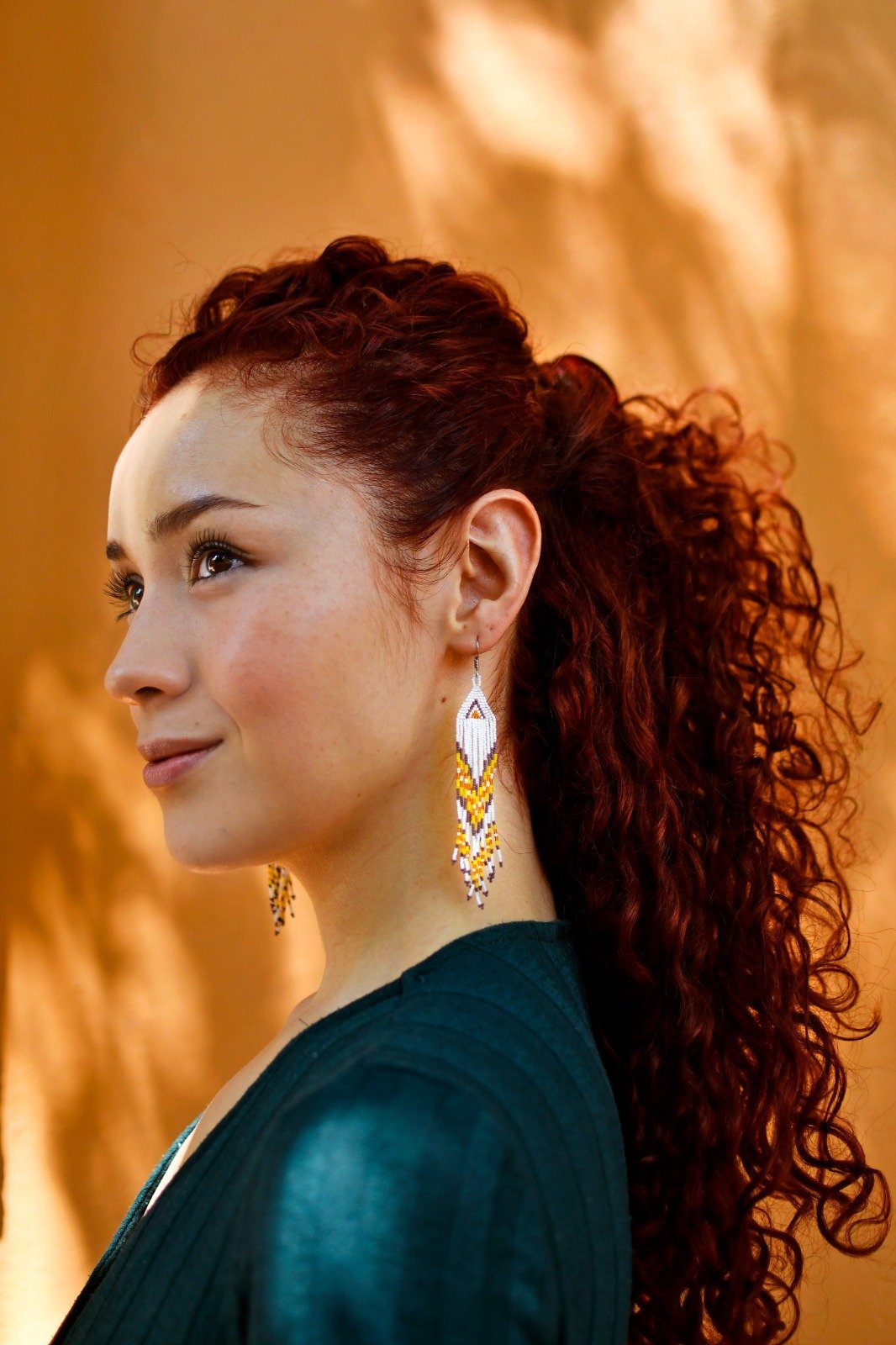 woman wearing white yellow brown red hawktail micro fringe beaded earrings