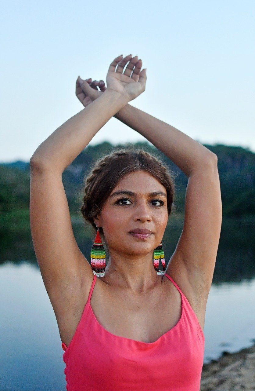woman wearing green red pink yellow white sarape fringe beaded earrings at dusk
