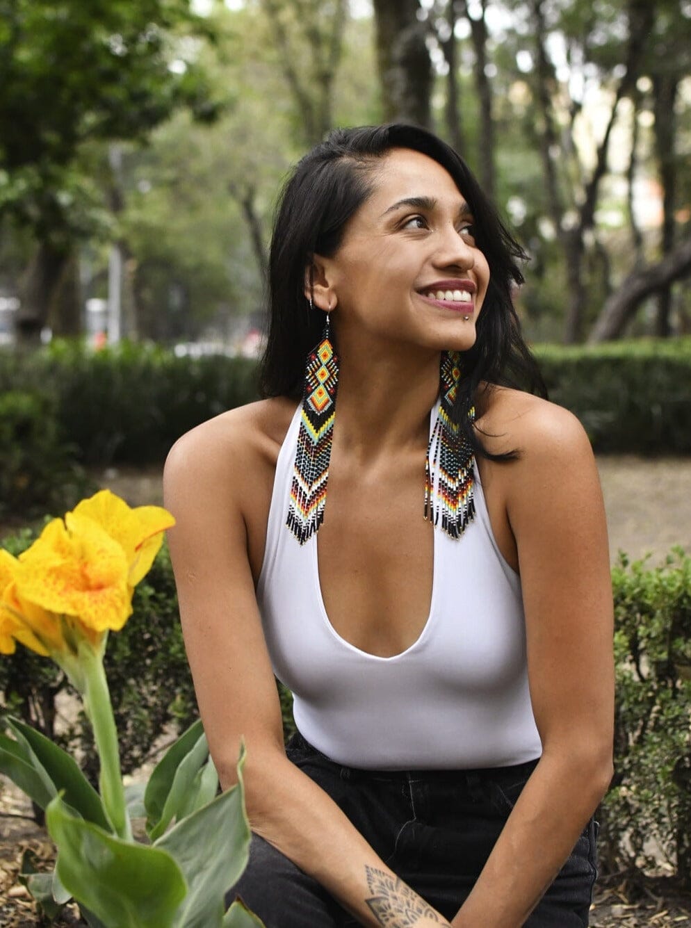Woman wearing long black yellow red beaded earrings