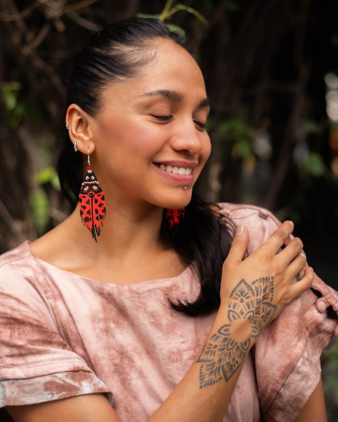 A woman wearing red black ladybug fringe handmade beaded earrings