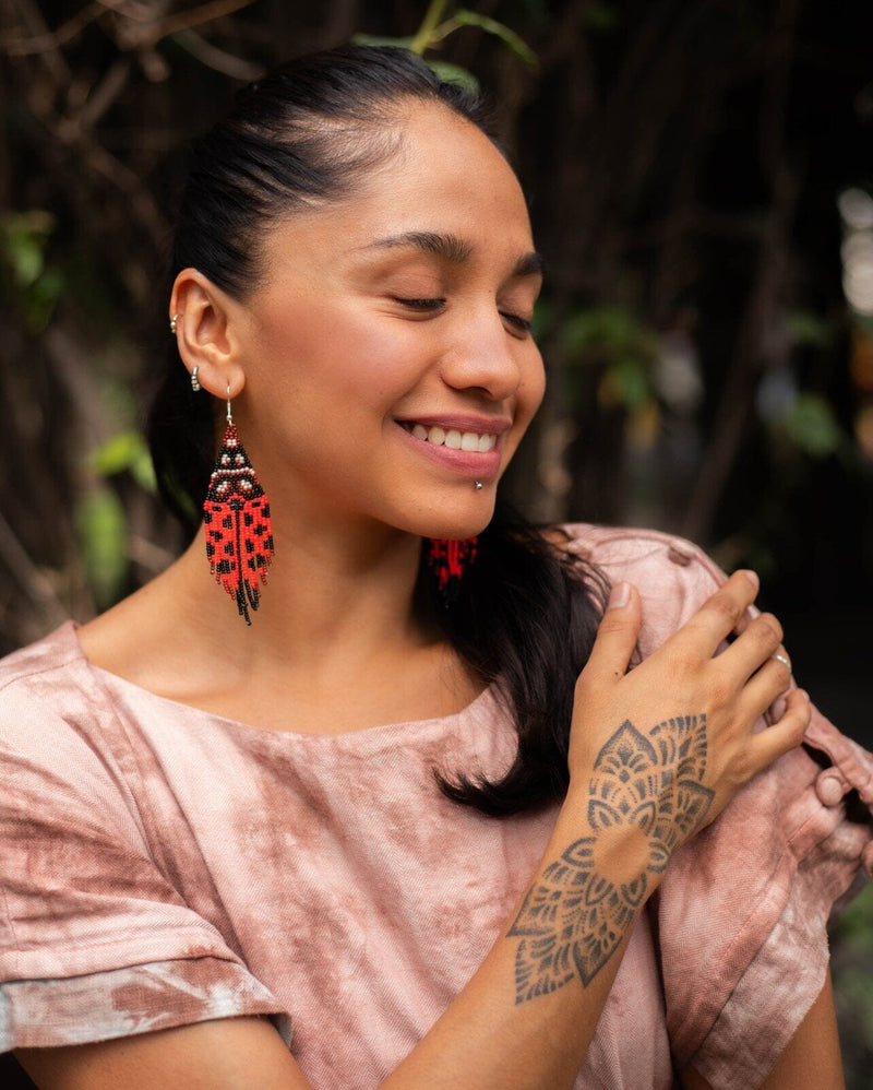 woman wearing red black ladybug fringe beaded earrings
