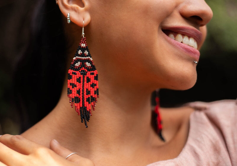 woman wearing red black ladybug fringe beaded earrings