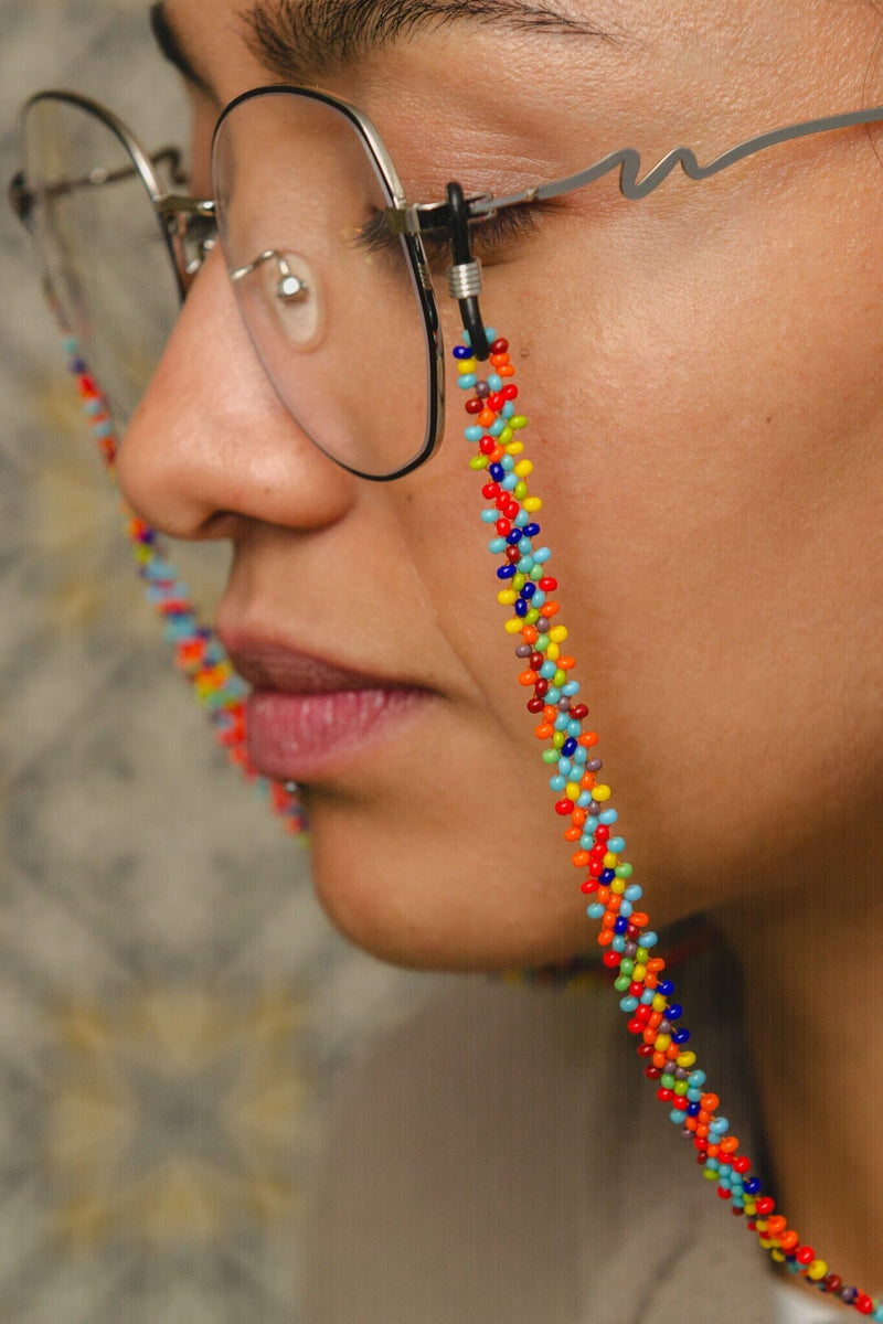 woman wearing confetti yellow red blue teal green beaded glasses chain jewelry