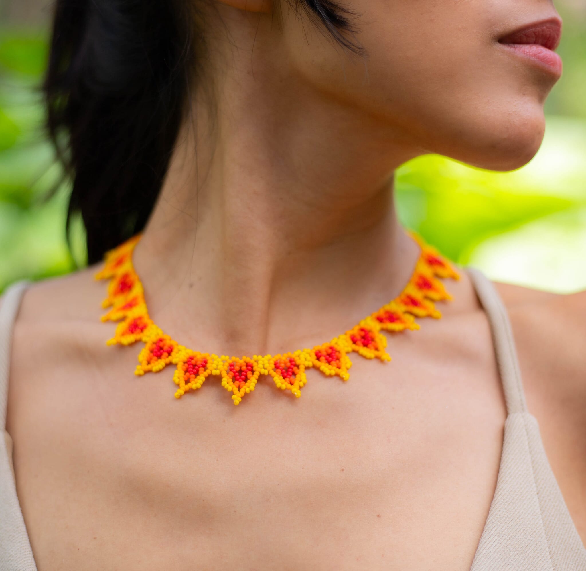 A woman wearing a golden berries yellow, orange, red beaded necklace, a piece of Native American handmade jewelry.