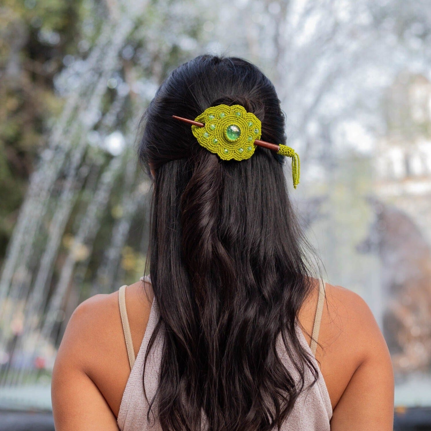 A woman wearing a key lime green beaded hair barrette and pin, a statement piece of Native American jewelry.