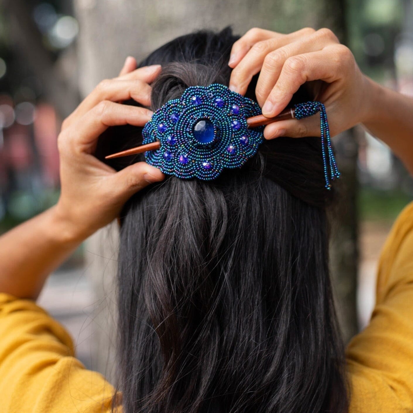 A woman wearing a midnight steel blue beaded hair barrette and pin, a statement piece of Native American handmade jewelry.