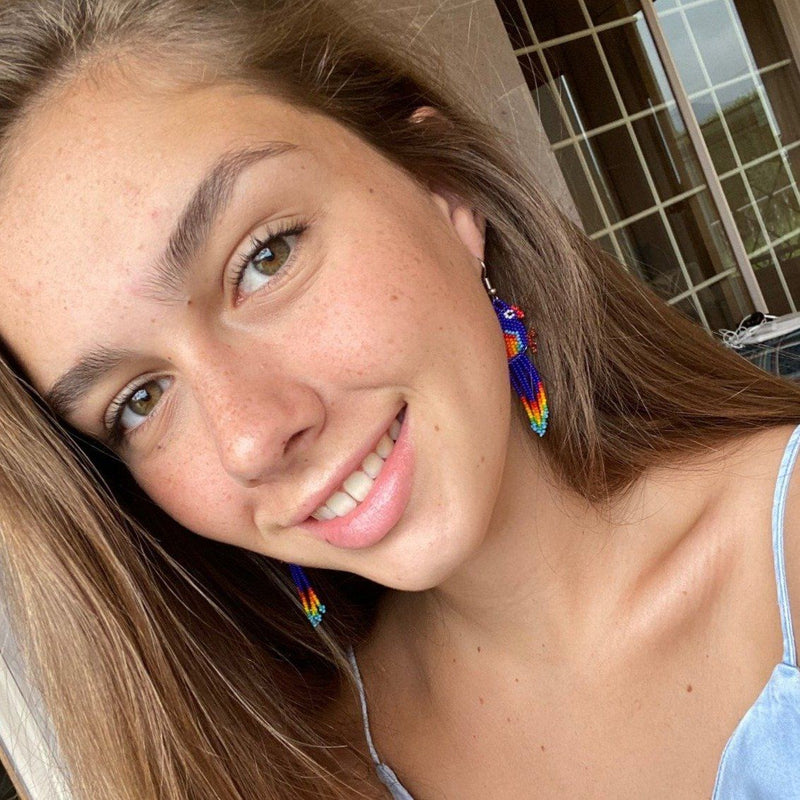 woman wearing bright blue bird beaded earrings selfie
