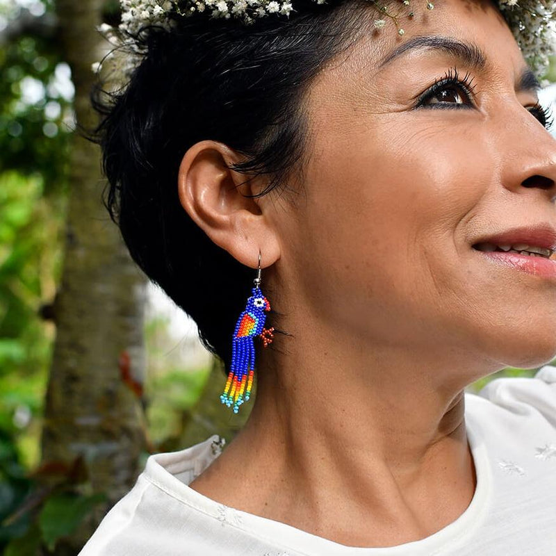 woman wearing bright blue bird beaded earrings