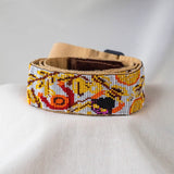 close up rolled up El Mercado beaded Guitar strap white yellow brown red orange adjustable leather on guitar 