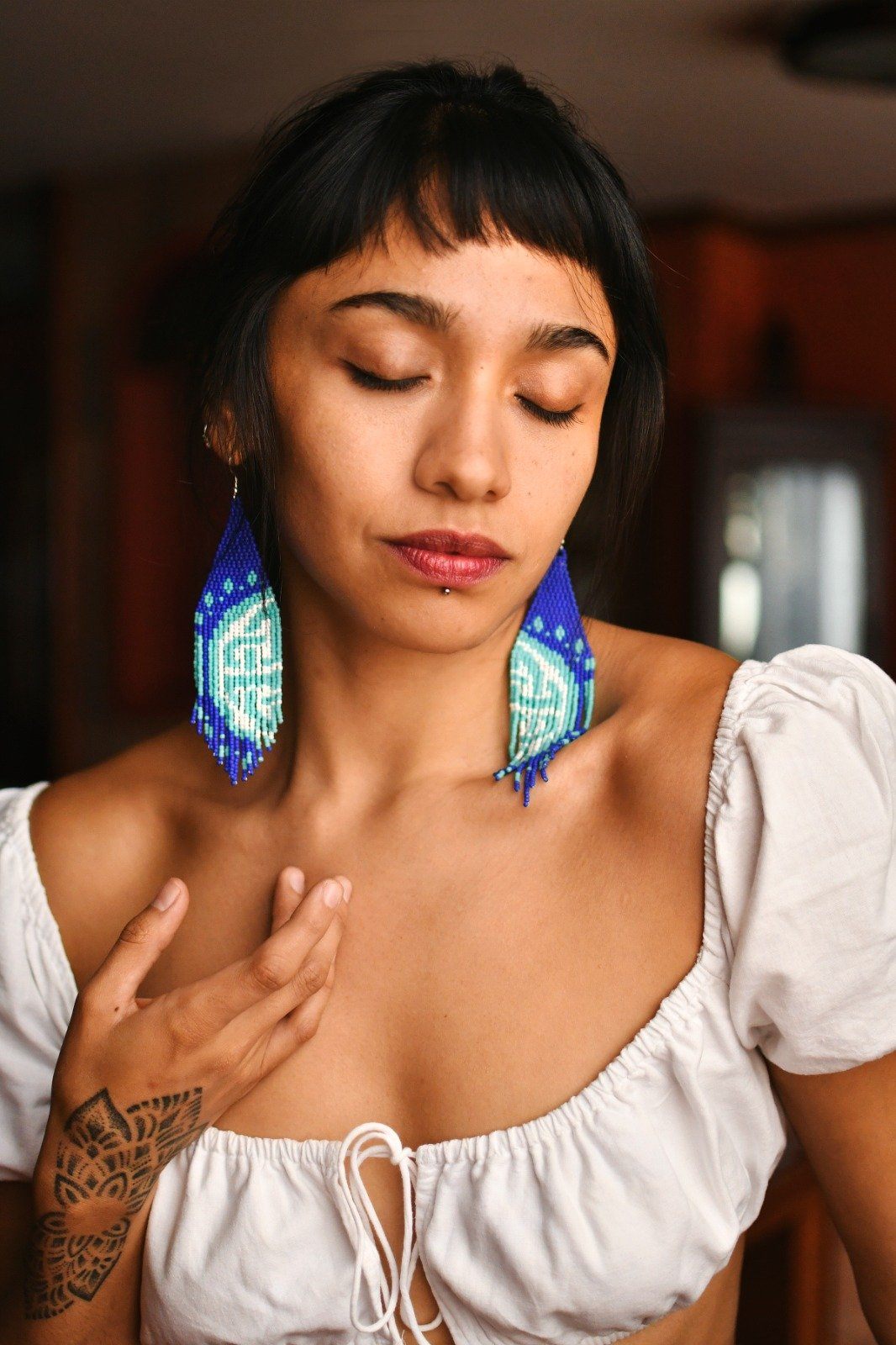 Woman Wearing a Handmade Blue And White Infinity Knot Fringe Beaded Earrings by Mother Sierra