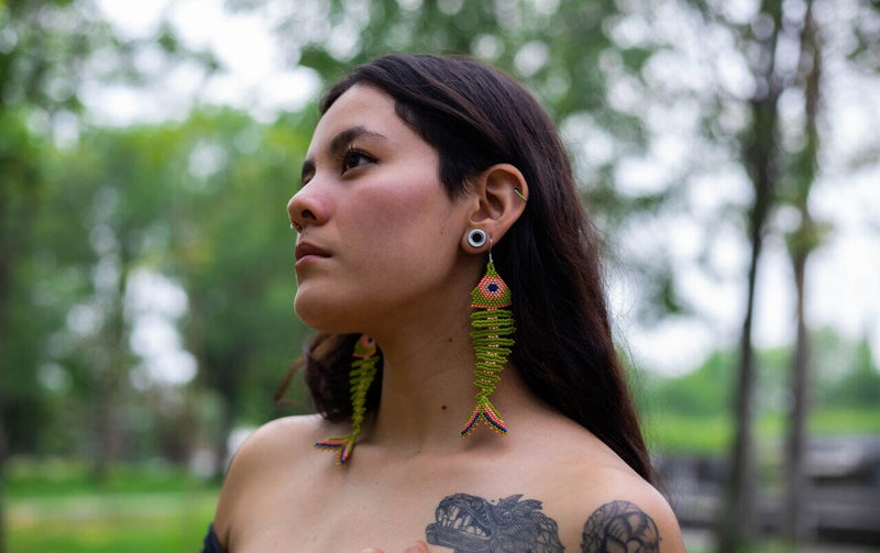 woman wearing pea green salmon pink fish skeleton fossil beaded earrings