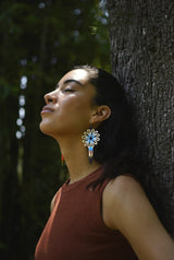 woman wearing Guanábana light blue eggshell white beaded earrings against tree trunk