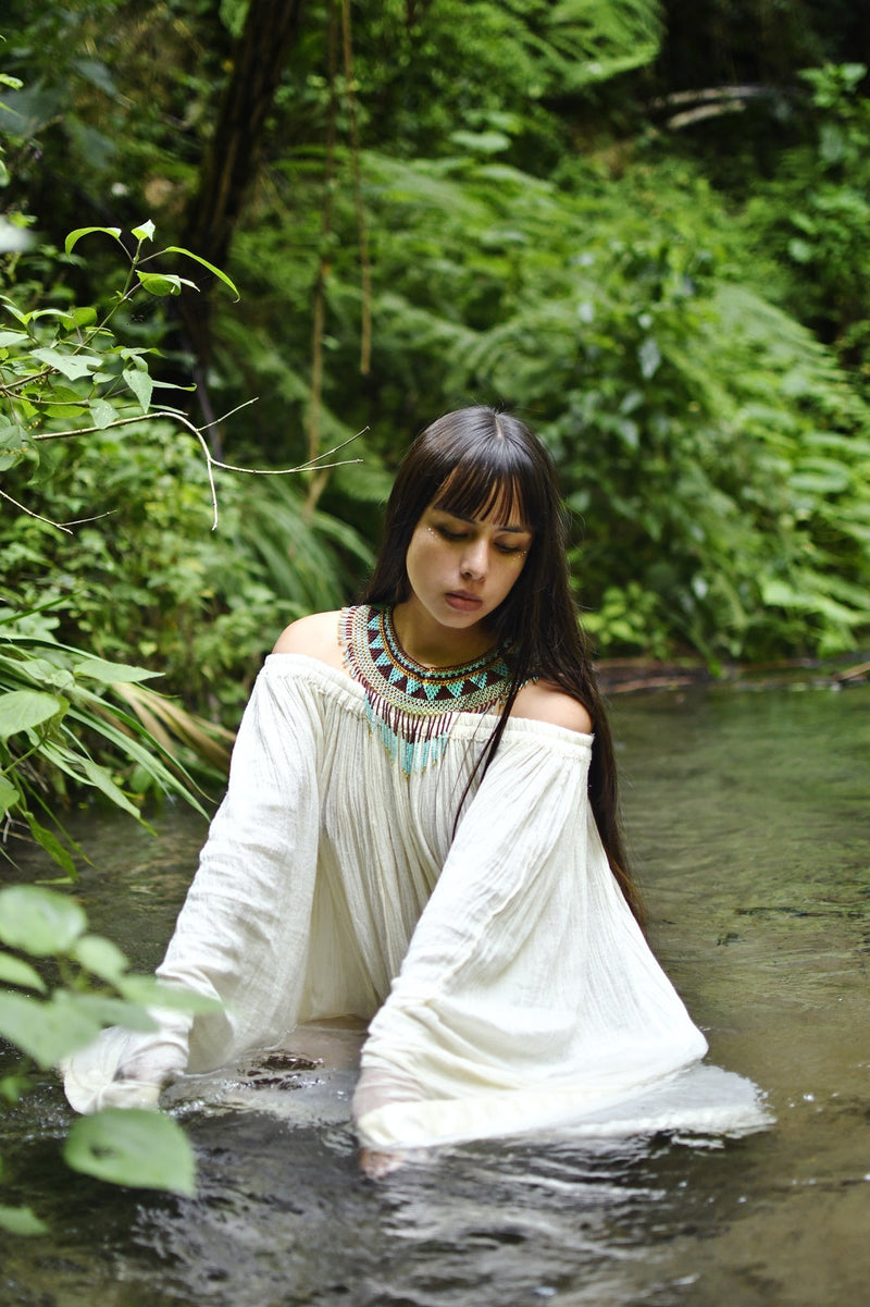 woman in river wearing jade green teal gold brown beaded choker necklace fringe native american jewelry
