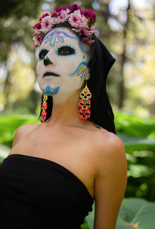 woman in day of the dead makeup wearing skull beaded earrings