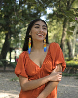 woman wearing orange yellow light blue fringe beaded earrings