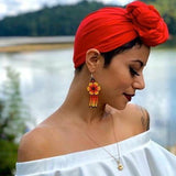 woman wearing yellow blossom beaded earrings with red head scarf