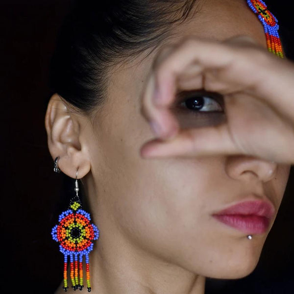 woman wearing psychedelic blossom blue green red beaded earrings