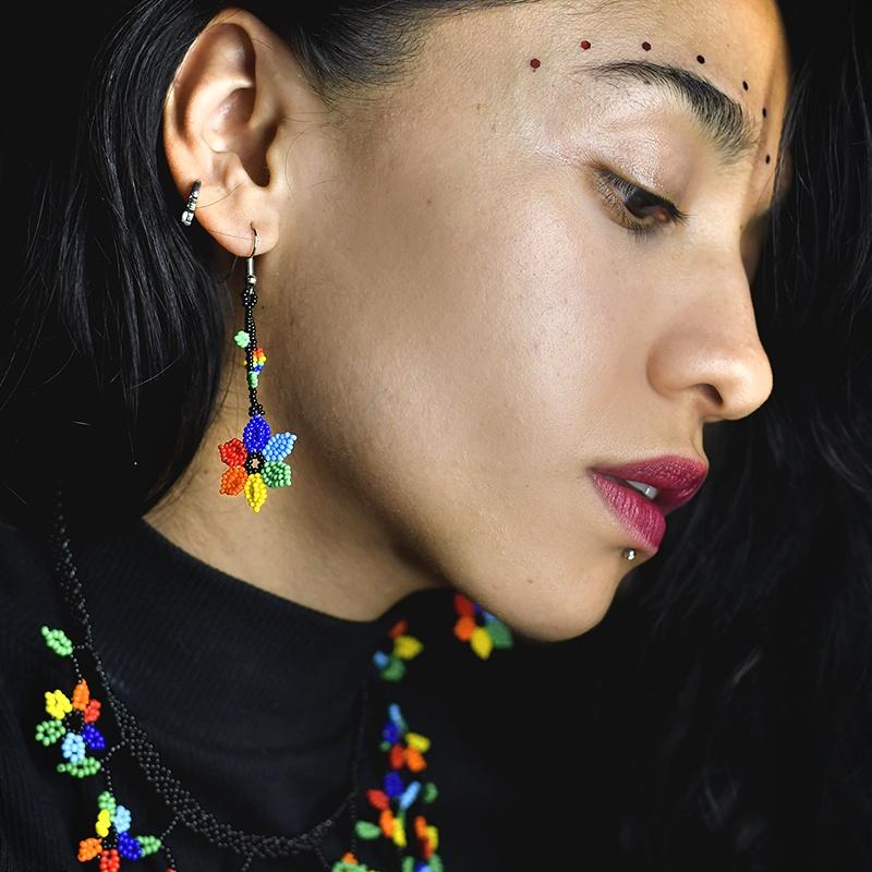 woman wearing rainbow flower dangle beaded earrings and rainbow florecitas necklace