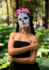 woman in day of the dead makeup wearing skull beaded earrings and flower crown